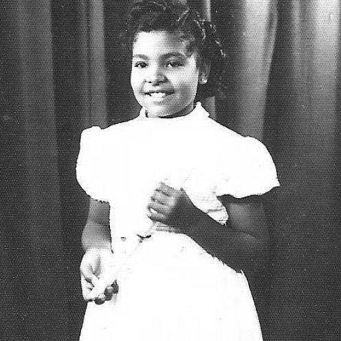 Na imagem, retirada do projeto, uma jovem menina negra, segura nas mãos um pequeno diploma e posa para a foto.