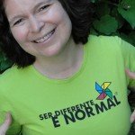 Patricia Almeida, sorrindo, vestindo com camiseta verde com a frase "Ser Diferente é Normal"