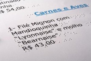 Detalhe de cardapio escrito e o relevo em braile correspondente por cima