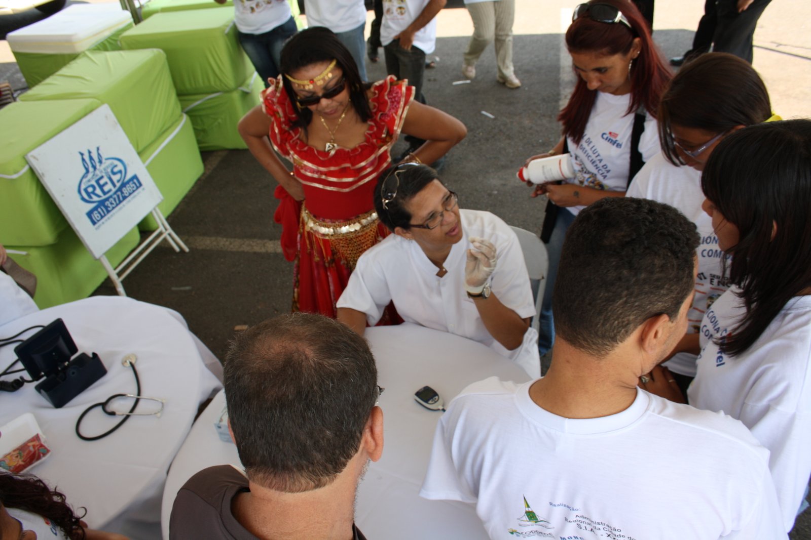 Profissional sentada a mesa oferece informacoes sobre saúde durante o festival a grupo de jovens
