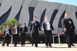 stj 3 moças e 3 rapazes de terno preto em primeiro plano caminhando para frente com o predio do Superior Tribunal de Justiça ao fundo