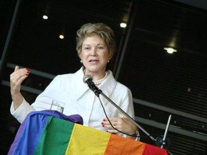 A senadora Marta Suplicy discursa tendo uma bandeira com arco iris a frente