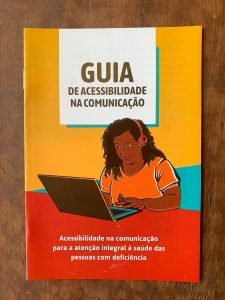 moça negra com síndrome de Down, com fone de ouvido, usando laptop. 