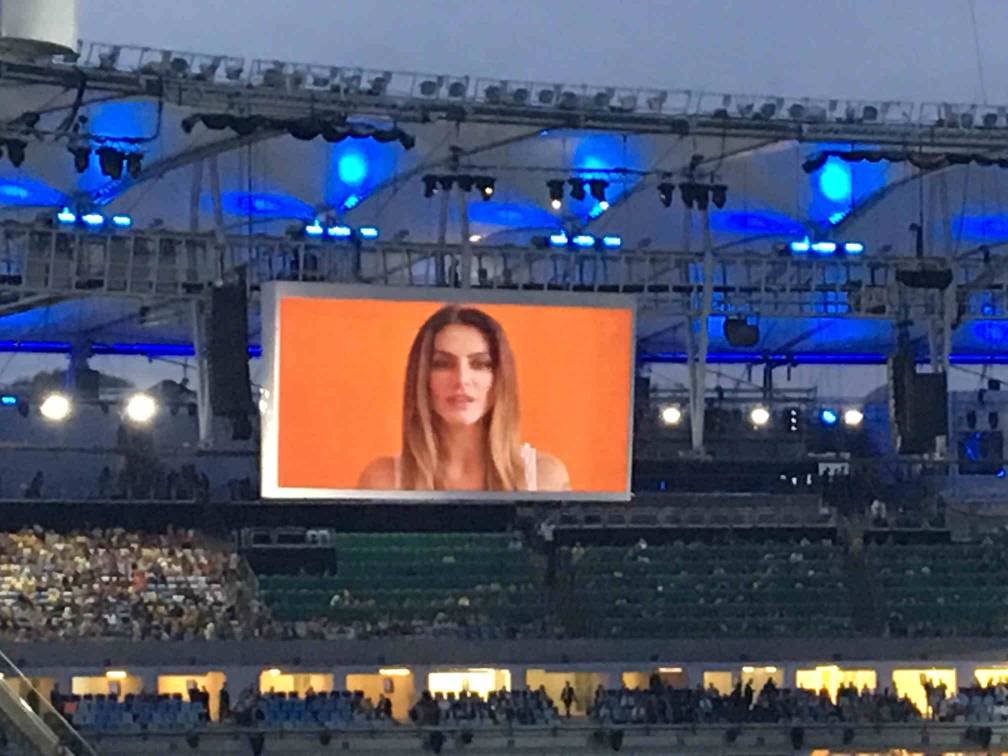 no estadio, telao mostra fundo laranja e o rosto da atriz cleo pires em primeiro plano.