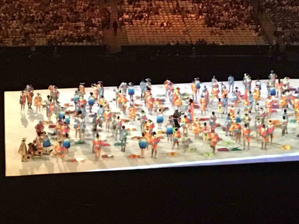 imagem de longe mostra varias pessoas com guarda-sois, vendedores de mate, cadeiras de rodas adaptadas, simulando uma praia.