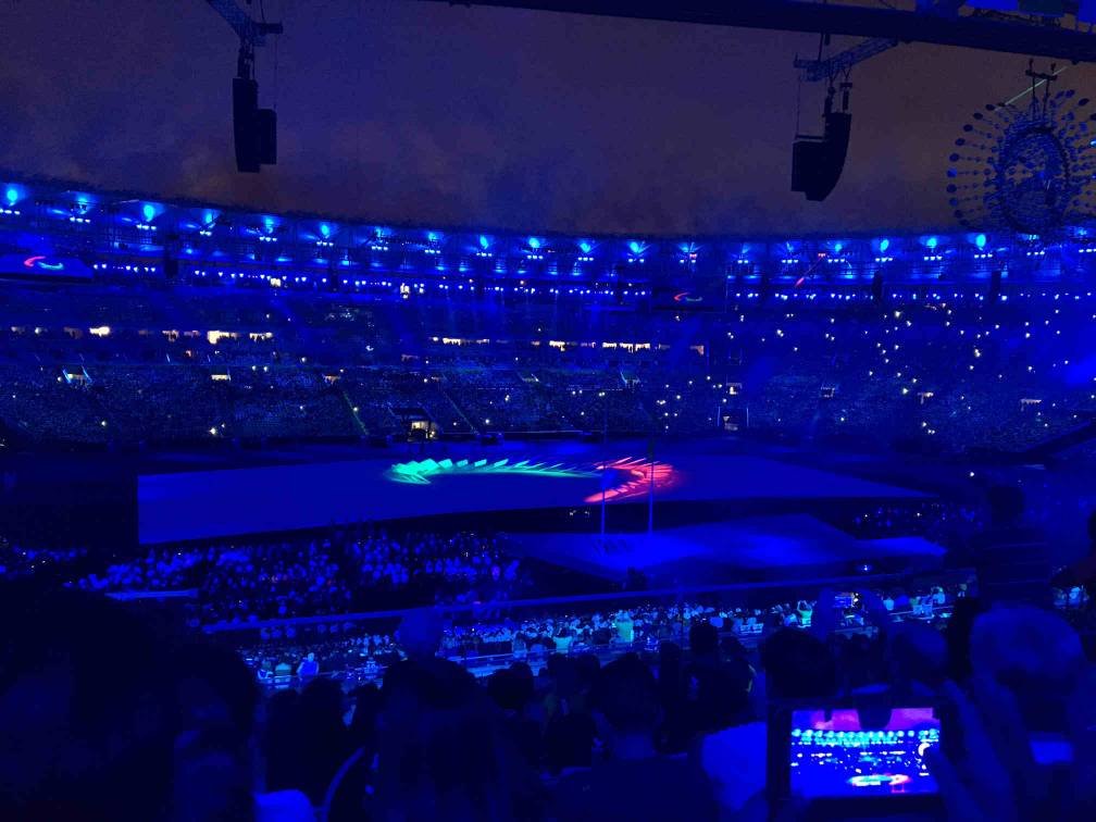 no estadio do maracana escuro, o simbolo dos jogos paralimpicos acesos nas cores verde, azul e vermelho.