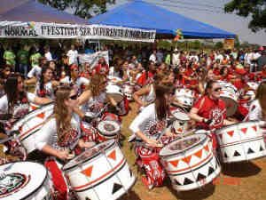 Grupo de percussão Batalá, formado por mulheres de roupas brancas vermelhas e pretas, tocando tambores e bumbos.