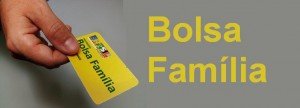Mão segurando cartao amarelo com letras verdes Bolsa Família e o logotipo Brasil