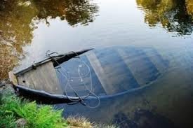 Canoa furada cheia de água na beira de um lago