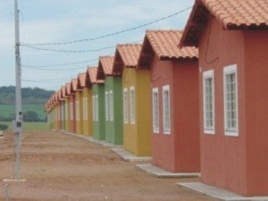 Fileira de casas populares de cores diferentes, uma ao lado da outra.