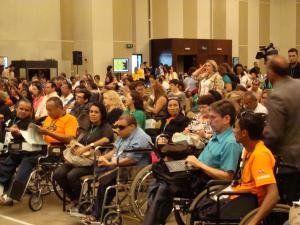 Delegados na plateia assistem a Conferencia, muitos em cadeiras de rodas.