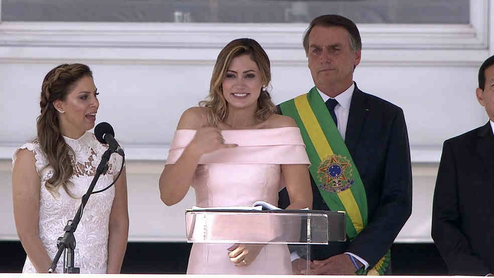 Imagem: captura. Michelle Bolsonaro discursa em libras à frente do presidente Jair Bolsonaro e ao lado de uma intérprete.