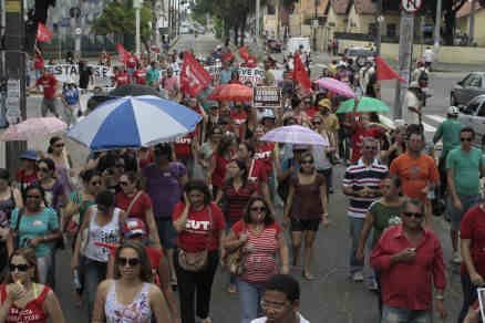 professores Professores em greve realizando passeata. Alguns carregam guarda-chuvas.