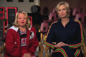 r-word-psa-300x200 Atrizes Lauren Potter e Jane Lynch, do seriado Glee, vestindo as roupas de ginástica de seus personagens, sentadas.