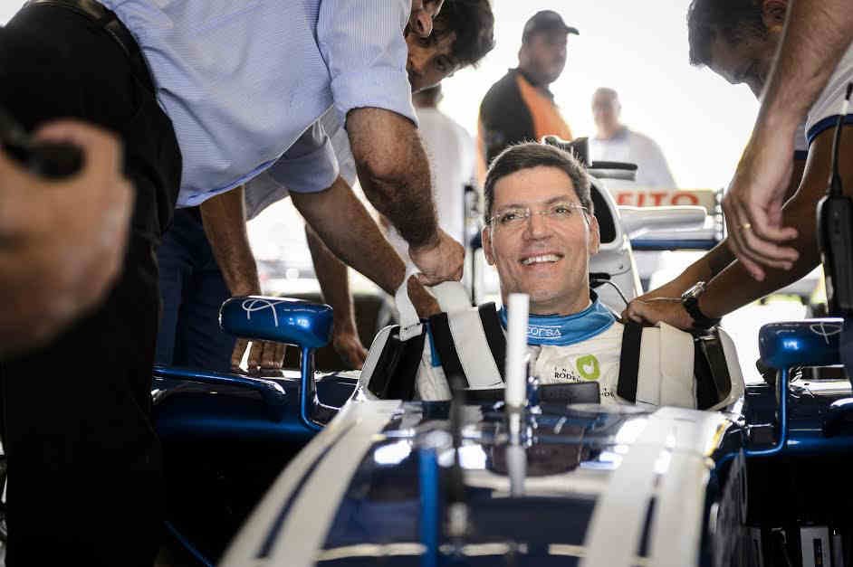 rodrigo mendes sentado em um carro de corrida, sorrindo.