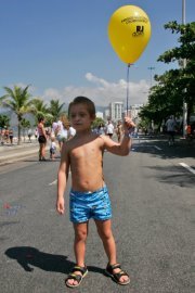 Menino de shor azul segurando um balão amarelo com a inscrição RJDown