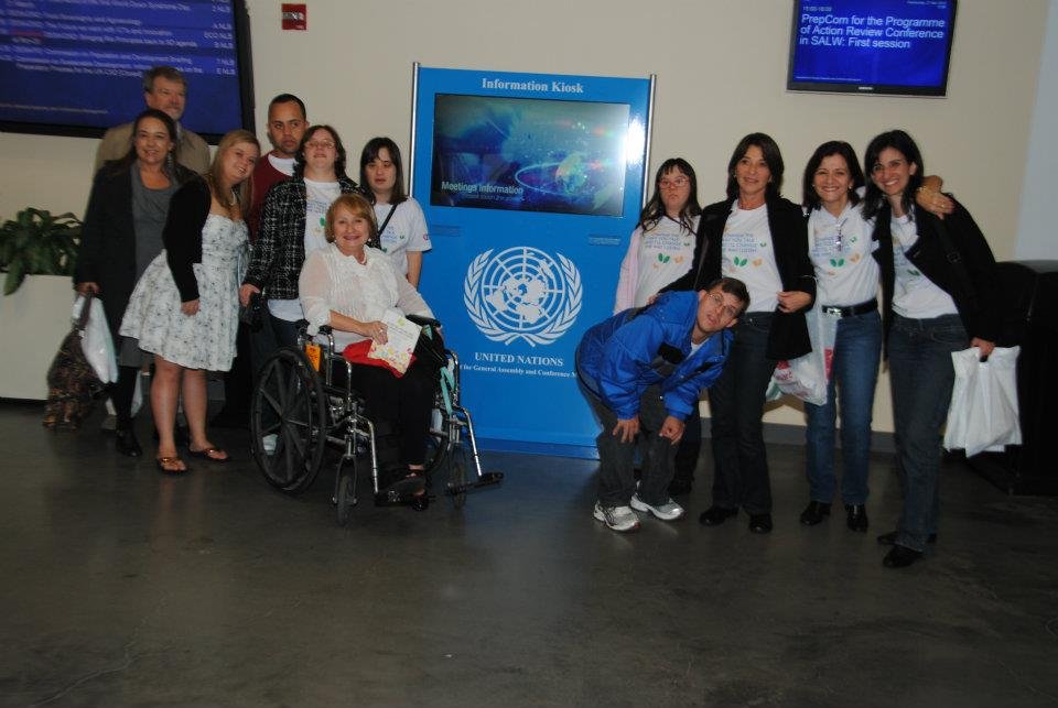 Grupo de pessoas em frente ao símbolo da ONU.