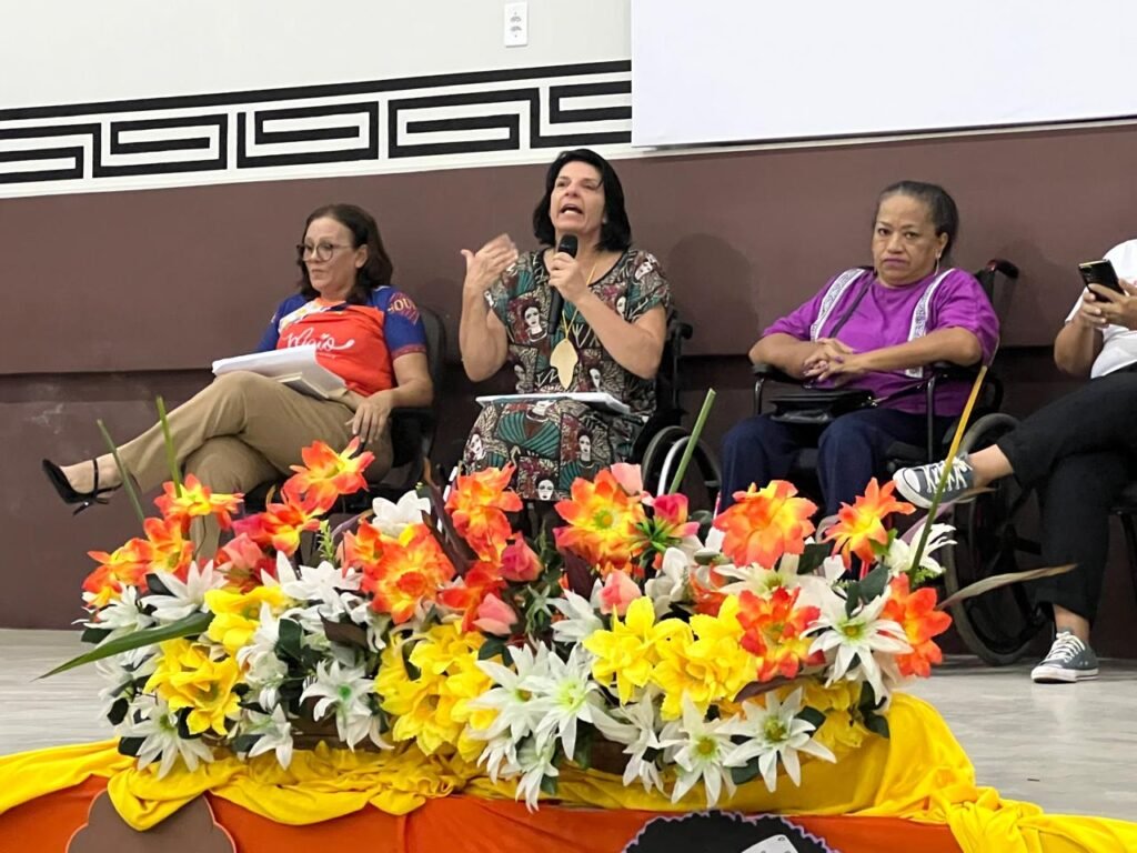 mulher em cadeira de rodas falando em palco.