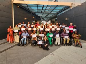 grupo de várias pessoas, em cadeira de rodas e cegos, com o certificado de conclusão da formação.