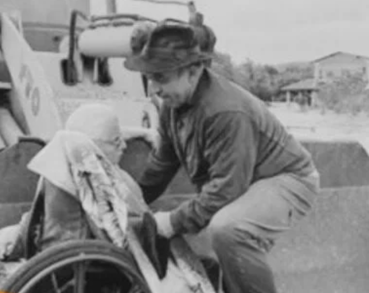 imagem preto e granca idosa em cadeira de rodas sendo resgatada.