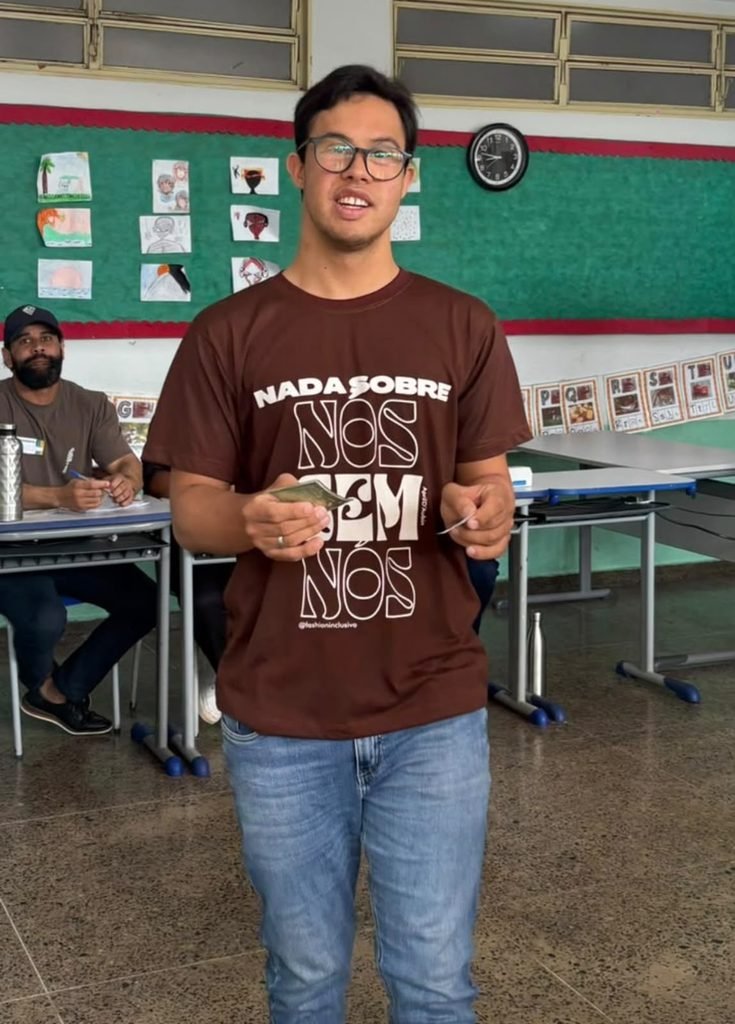 Luiz eduardo com camiseta escrita nada sobre nós sem nós, título de eleitor e comprovante da mão, saindo da urna.